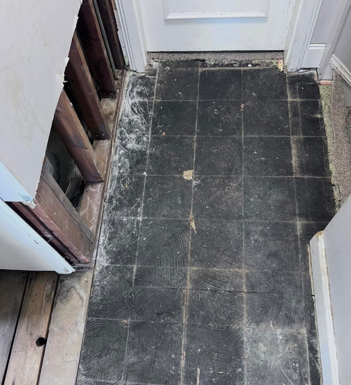 Vinyl flooring and baseboard removed down to subfloor in a water damaged doorway